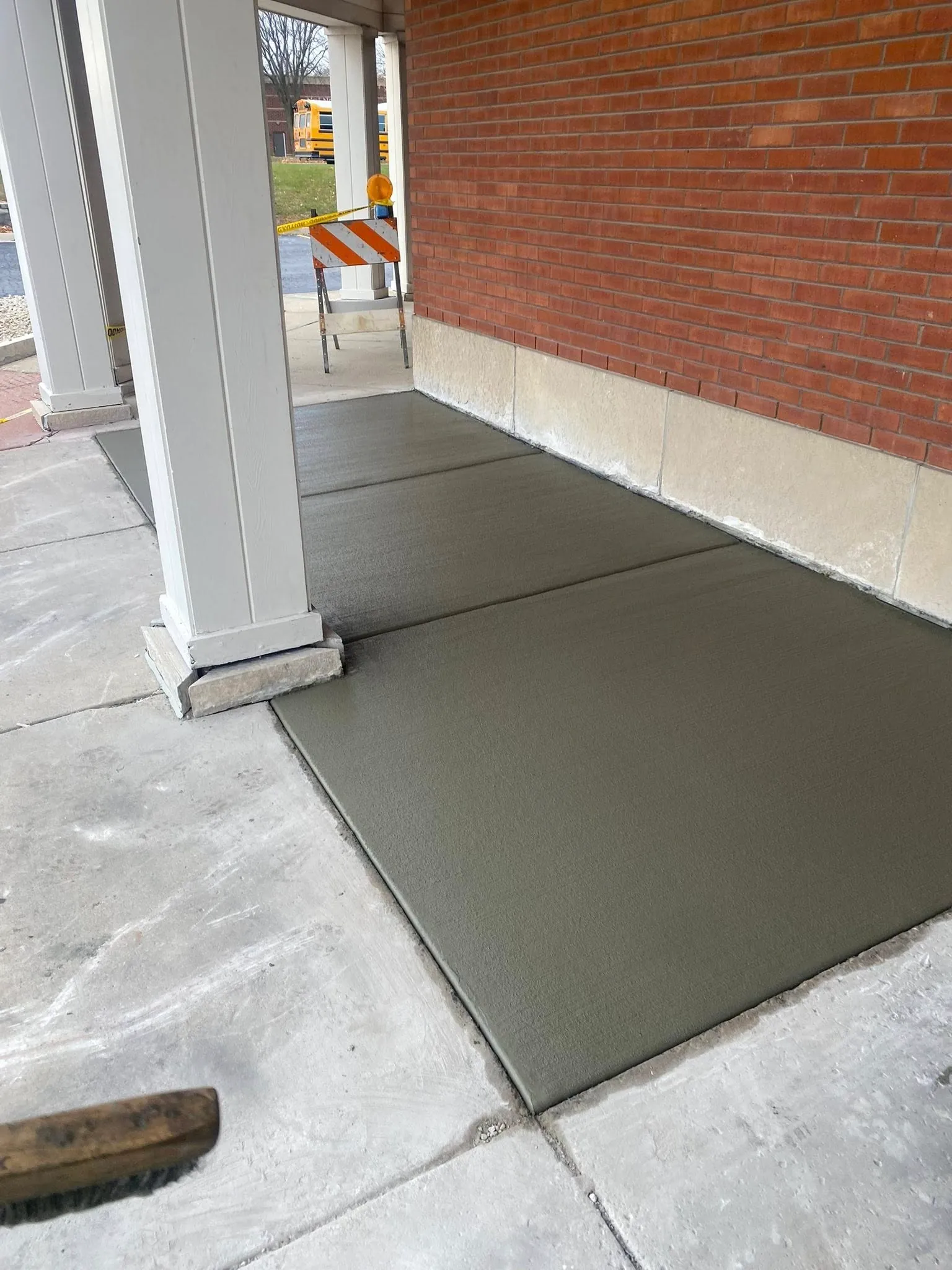 Clean broom-finished concrete walkway beside a brick building